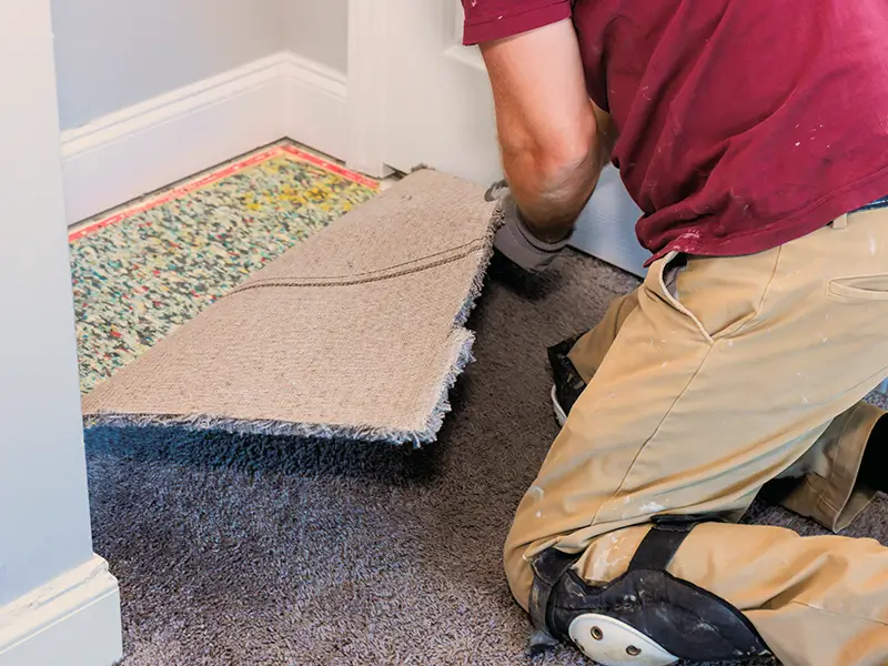 Worker removing an old carpet and pad