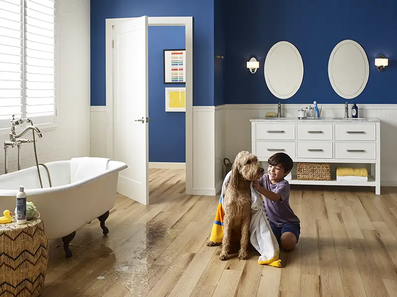 Waterproof vinyl flooring in bathroom where a child is drying a dog after a bath with water on the floor